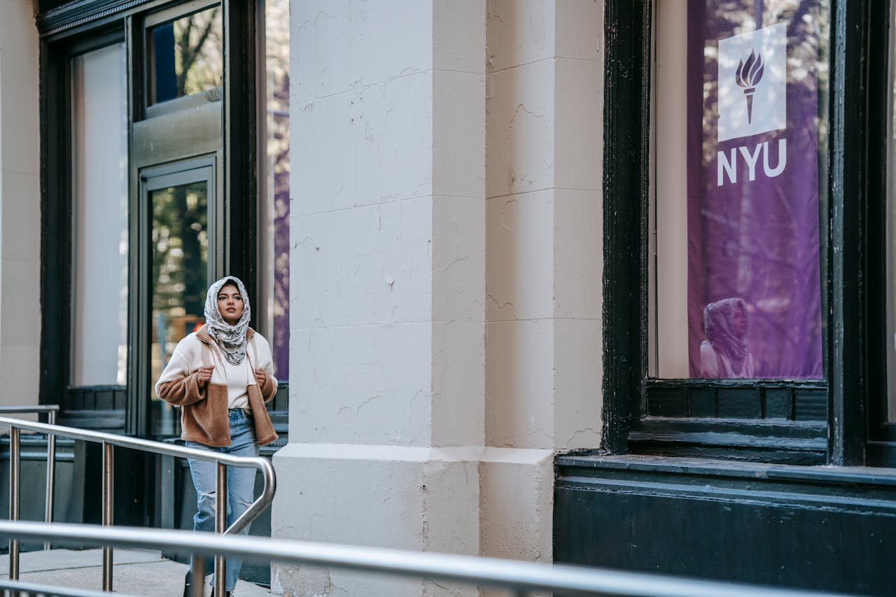 Young Muslim woman walking outside NYU, showcasing urban lifestyle and fashion.